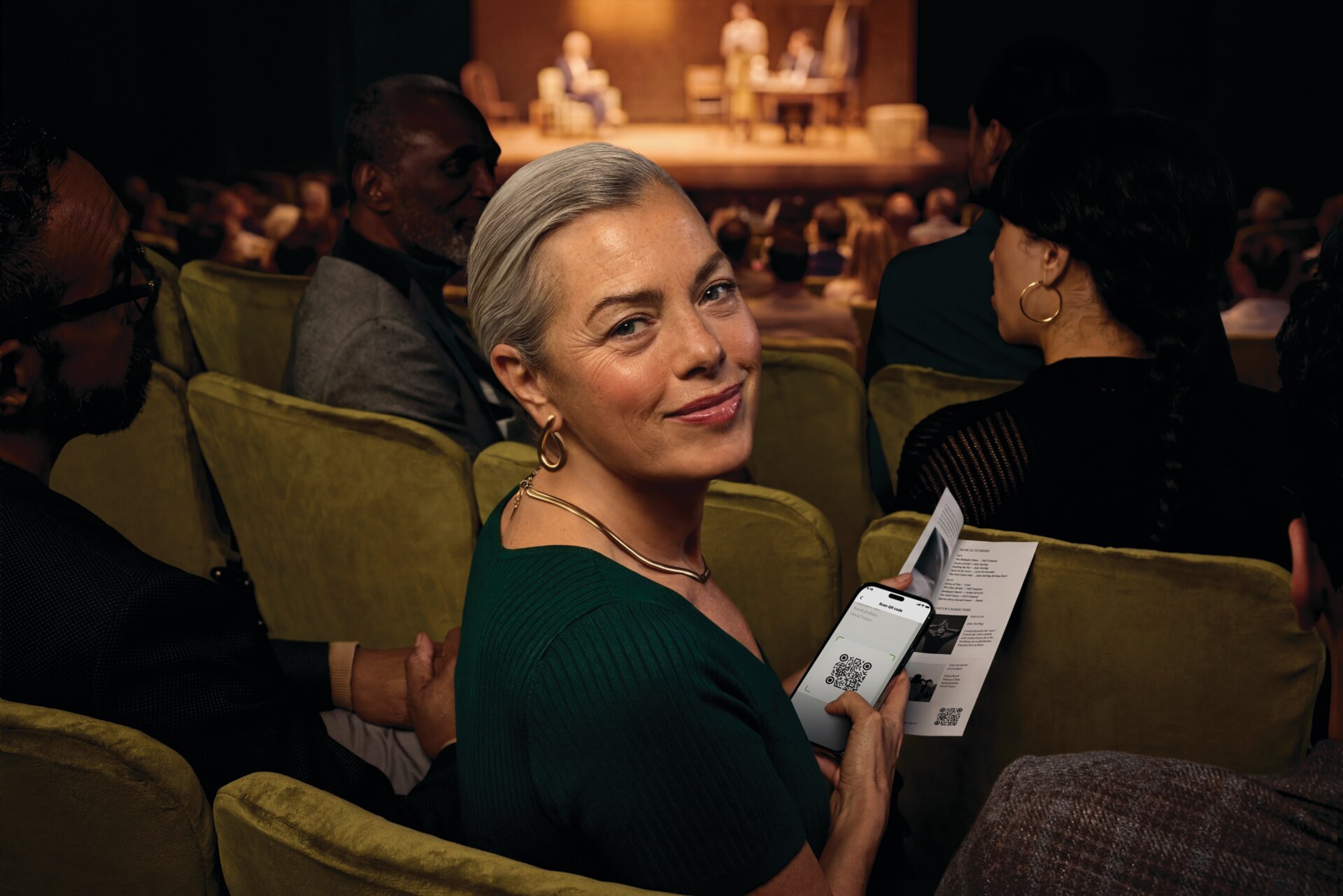 Person wearing a hearing aid while using a smartphone at a live event.