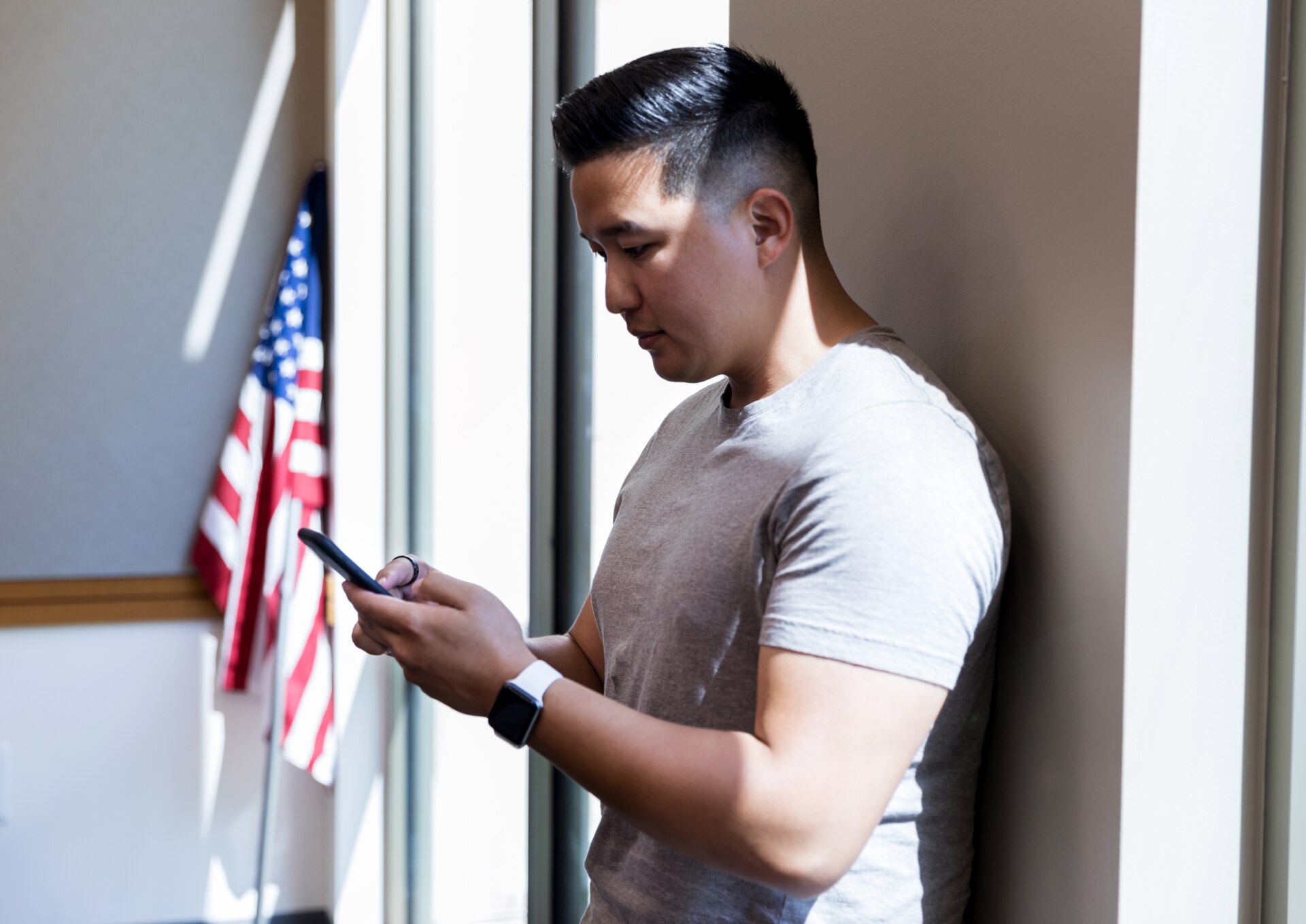 Military veteran looking at phone in front of American flag